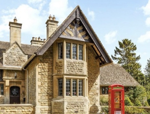 English Cottage style stone house with steep gables and small grouped casement windows.
