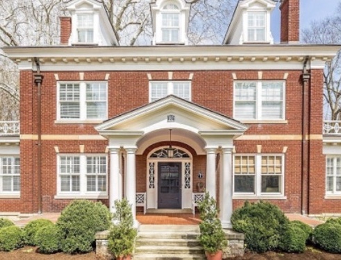Symmetrical brick Colonial Revival house with white multi-pane windows and a columned entrance.